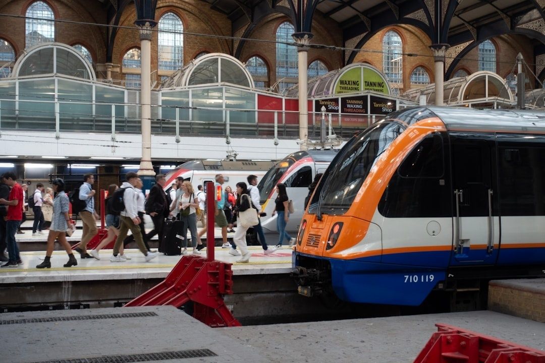 Train orange et bleu à quai dans une gare animée